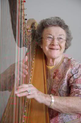 Senior woman playing the harp, smiling