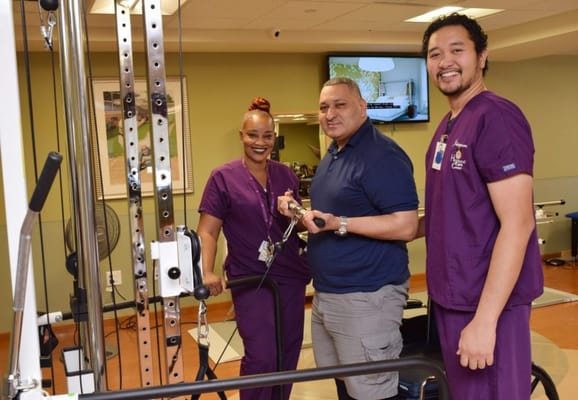 Therapists assisting a resident in rehabilitation equipment