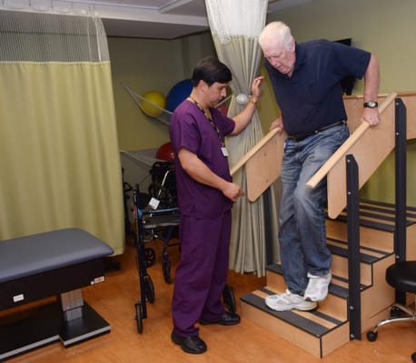 Therapist assisting a resident with stairs in an activity room