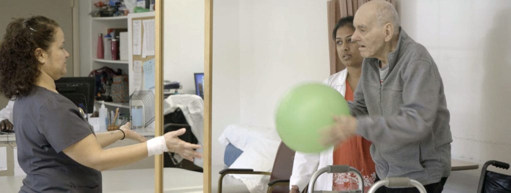 A resident participating in a physical therapy session with staff