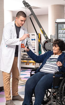 A therapist assisting a resident with rehabilitation equipment
