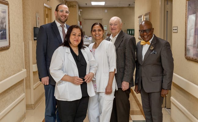 Staff and a resident smiling in a hallway