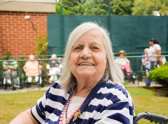 Resident smiling in an outdoor area with others in the background