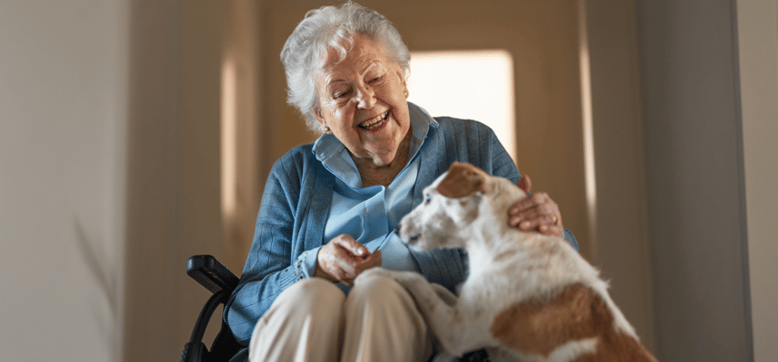 A senior woman interacting with a dog in a hallway