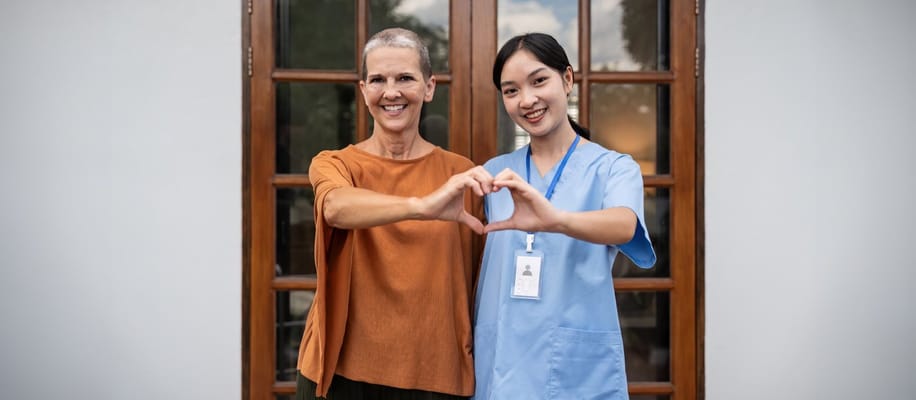 A staff member and resident making a heart shape with their hands