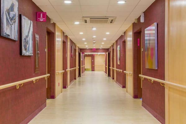 A well-lit corridor with red walls and art