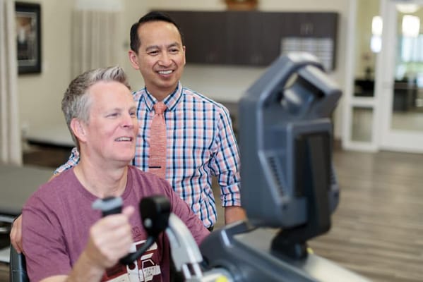 Resident using therapy equipment with staff supervision