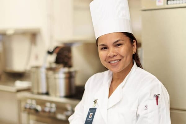 A staff member in a kitchen setting, smiling