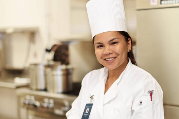 A staff member in a kitchen setting, smiling