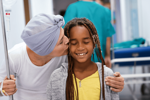 A caregiver kissing a young girl in a hospital hallway