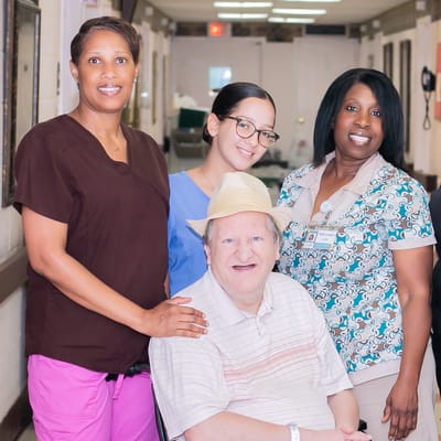 Staff and resident posing in a facility hallway