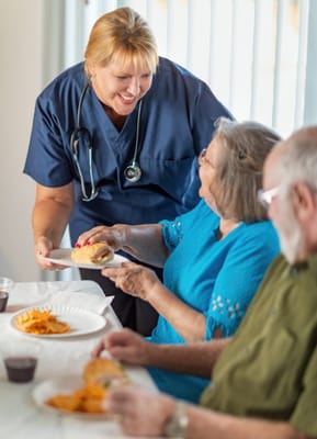 Staff serving food to residents in a dining area
