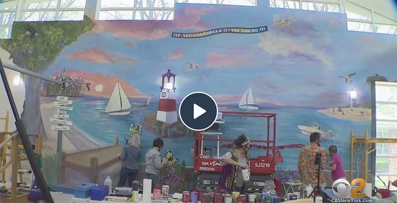 Artists painting a large mural in an activity room