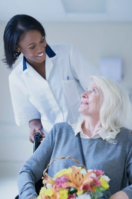 Caregiver smiling at a resident in a wheelchair