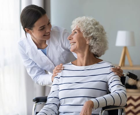 Caregiver smiling with a resident in a wheelchair