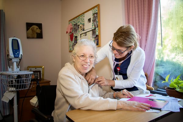 A staff member assisting a smiling resident in a cozy room