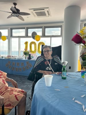 Residents celebrating a 100th birthday in a festive setting