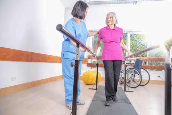 A caregiver assisting a senior woman in a rehabilitation area