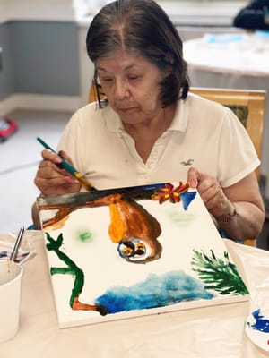 Resident painting on a canvas during an activity session