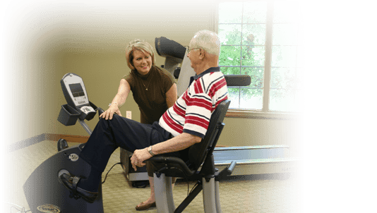A staff member assisting a resident with exercise equipment