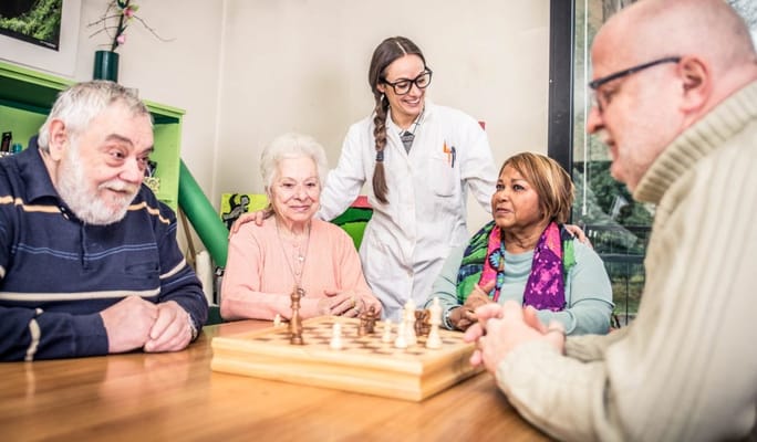 Residents and staff playing chess in an activity room