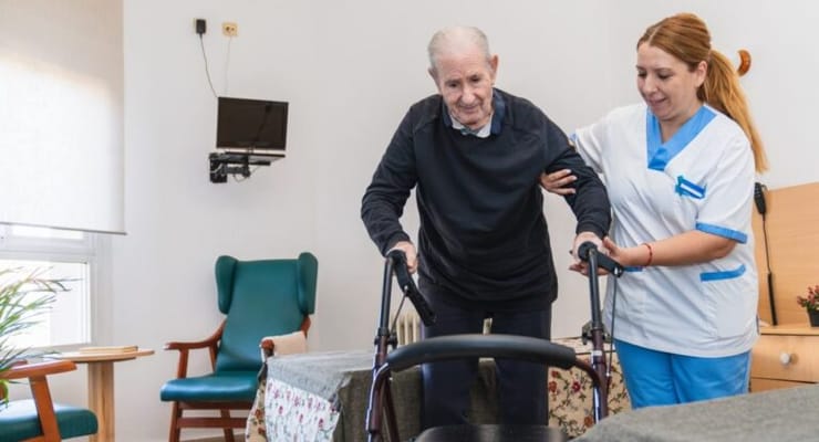 Staff assisting a resident with mobility in a facility room