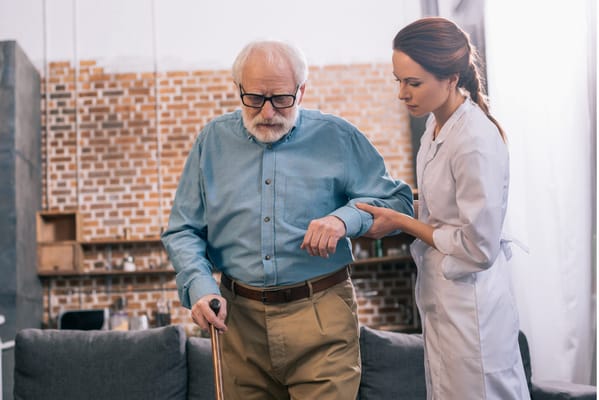 Caregiver assisting an elderly man in a living room