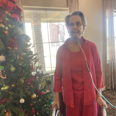 Resident standing by a decorated Christmas tree