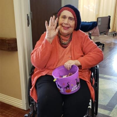 Resident waving with a candy bucket in a cozy room