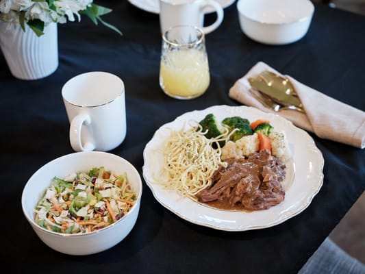 A dining table set with a meal including salad and entree