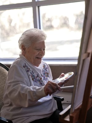 Senior resident painting in a bright activity room