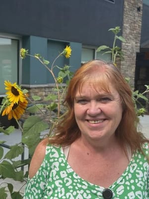 Woman smiling by sunflowers in a garden