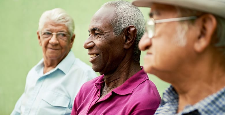 Three senior men smiling together outdoors