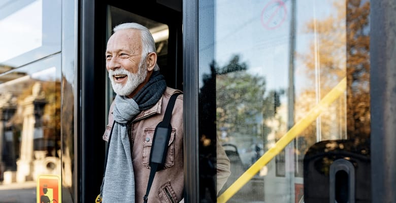 Senior man smiling as he exits a bus
