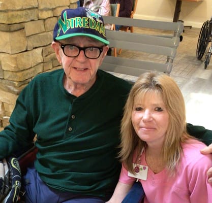 A resident and staff member in a facility lounge