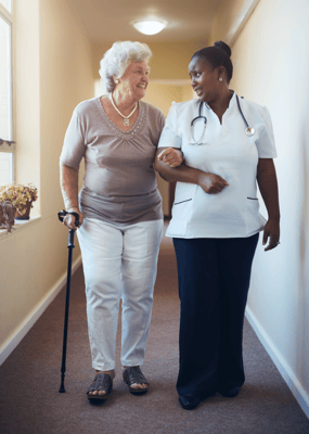 Resident and staff member walking in a hallway
