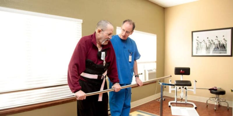 A resident and staff member using rehabilitation equipment