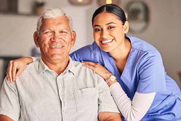 A caregiver posing with a smiling resident