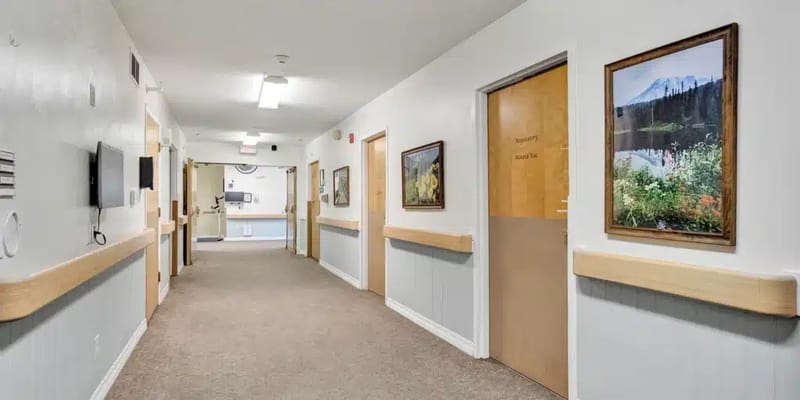 A well-lit hallway with room doors and artwork