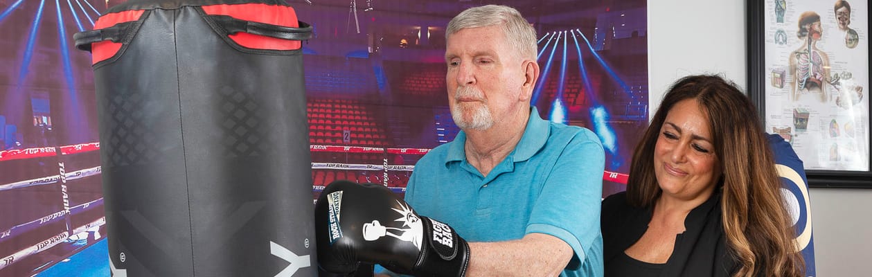 Senior resident boxing with staff in an activity room