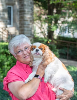 Senior woman holding a dog in a garden