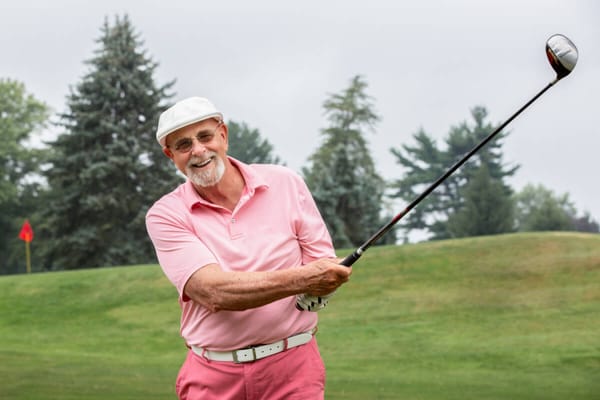 Senior man smiling and playing golf outdoors