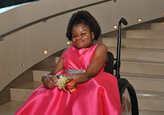 A young woman in a pink dress seated on steps