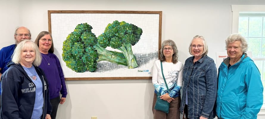 Residents posing beside a broccoli-themed artwork