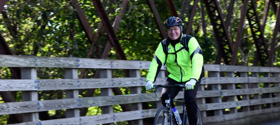 An older man riding a bicycle on a wooden bridge
