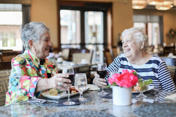 Two residents toasting with glasses of wine in the dining room