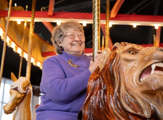 Senior woman smiling on a carousel horse