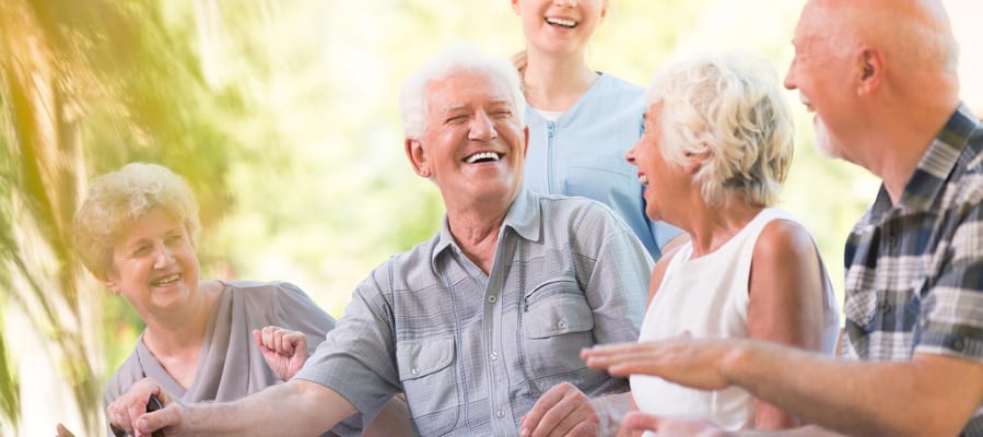 Seniors enjoying a laugh in a sunny outdoor setting