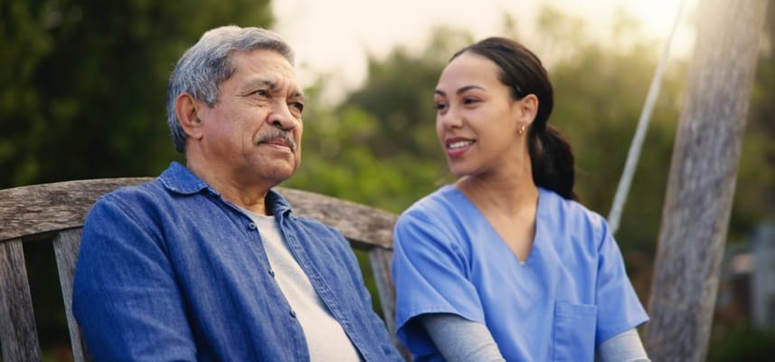 Senior resident sitting with caregiver in outdoor space