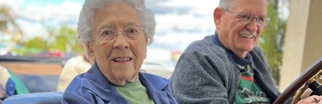 Two smiling seniors enjoying a drive in a car